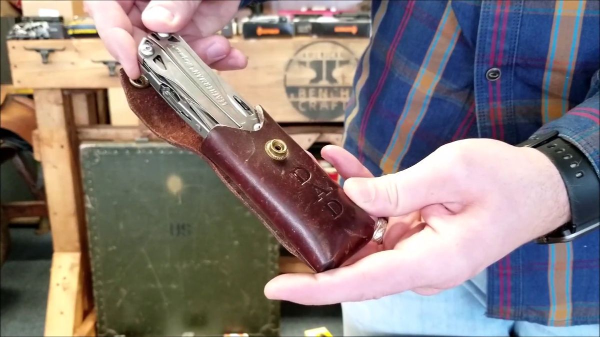 A man in workshop holding a leather sheath with "Dad" monogram for his multi-tool