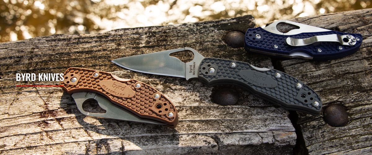 Three Byrd knives, one with the blade open, laying on an old wood bridge