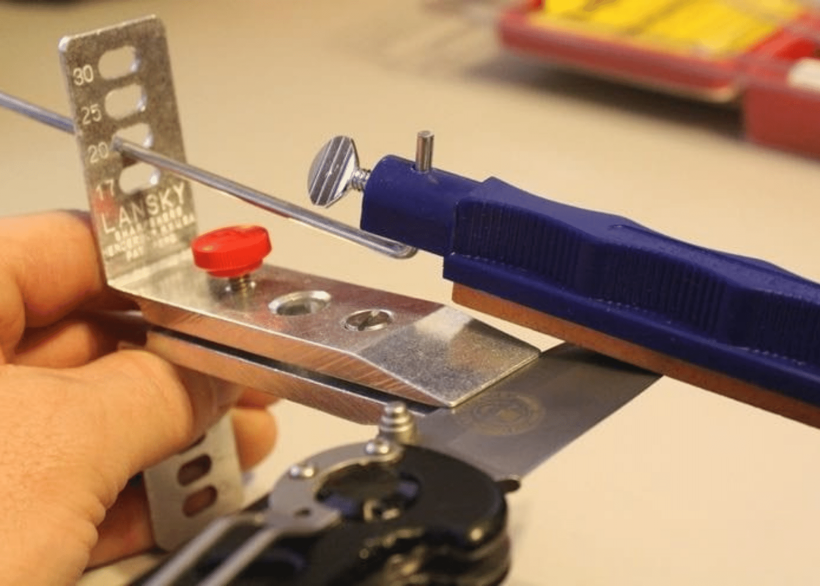 A knife clamped in a Lansky sharpener and a man working on sharpening the blade