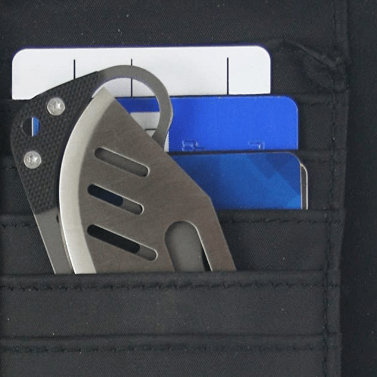 A wallet knife folded shown inside a wallet credit card slot with credit cards