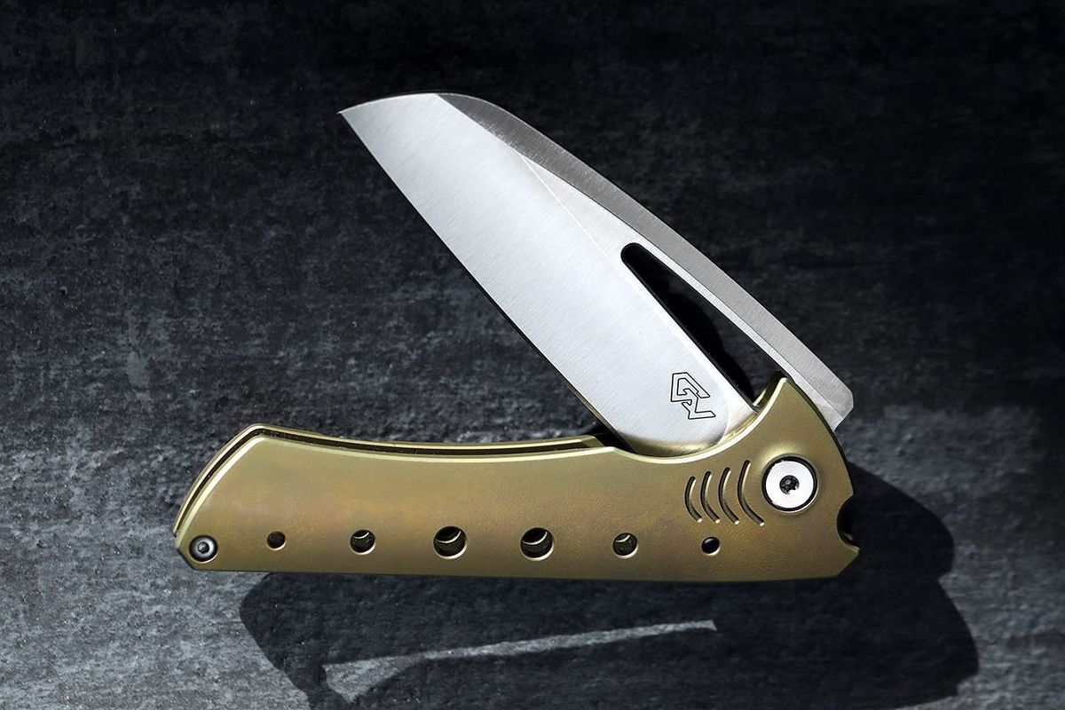 A Wharncliffe stainless steel folder with gold scales on a black countertop 