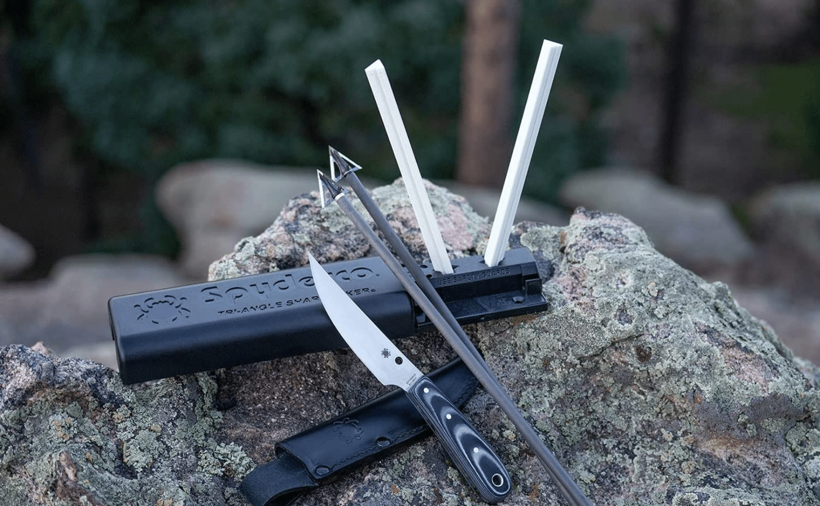 Sharpening rods with a fixed blade knife and arrows sitting on a rock