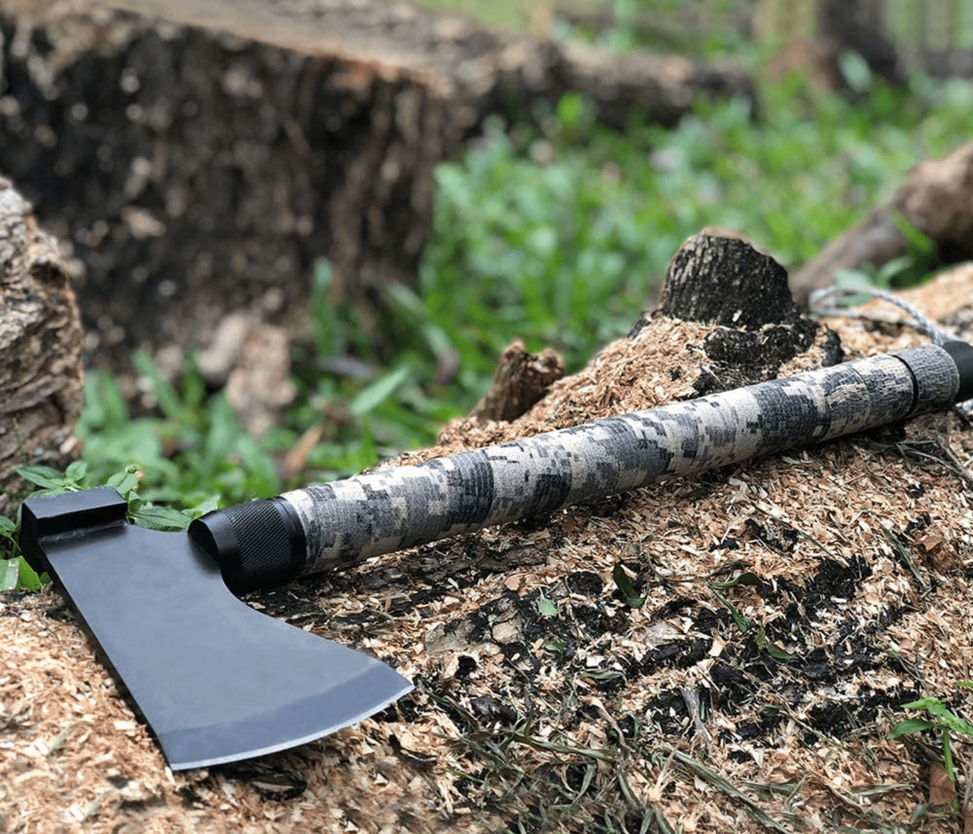 A small survival axe laying on a fallen tree in the woods