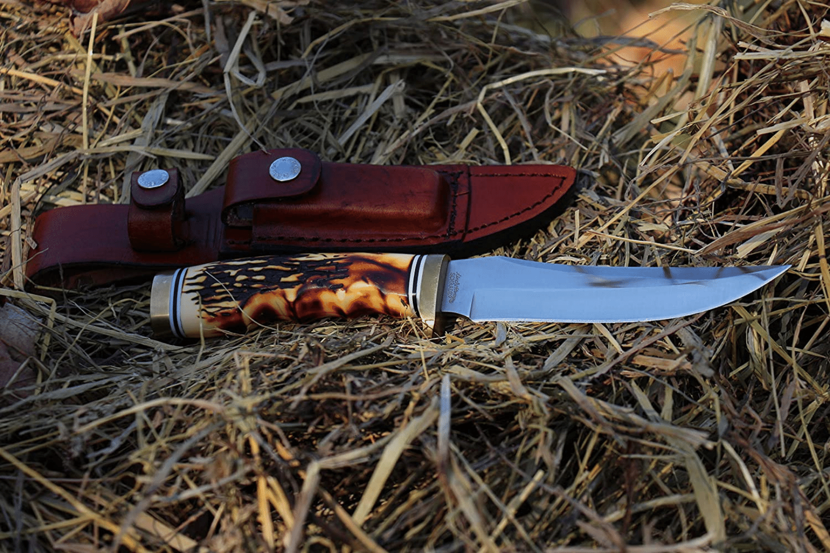 Bone handle knife and sheath with sharpening stone on hay bale
