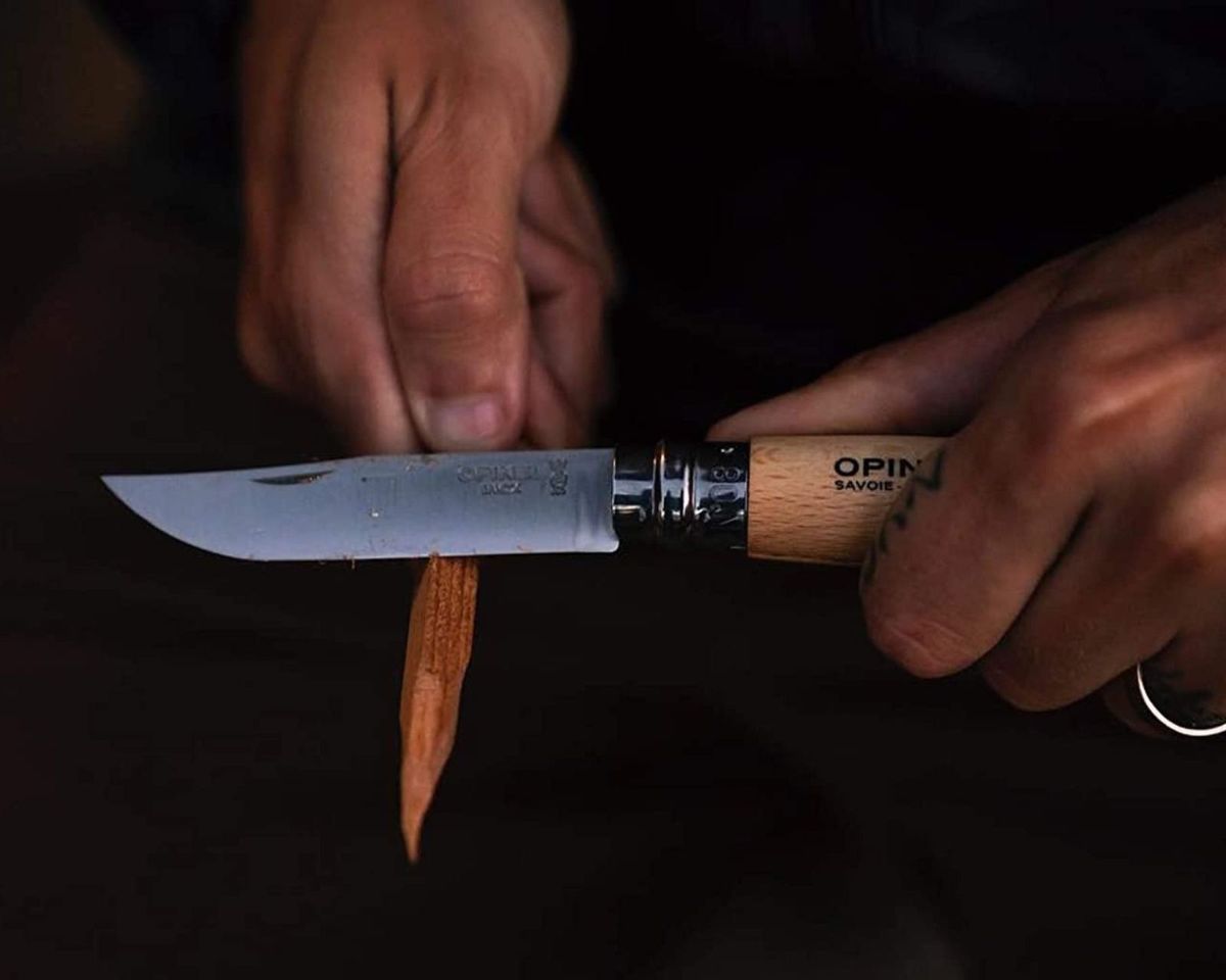 Someone sharpening a piece of wood with a pruning knife.