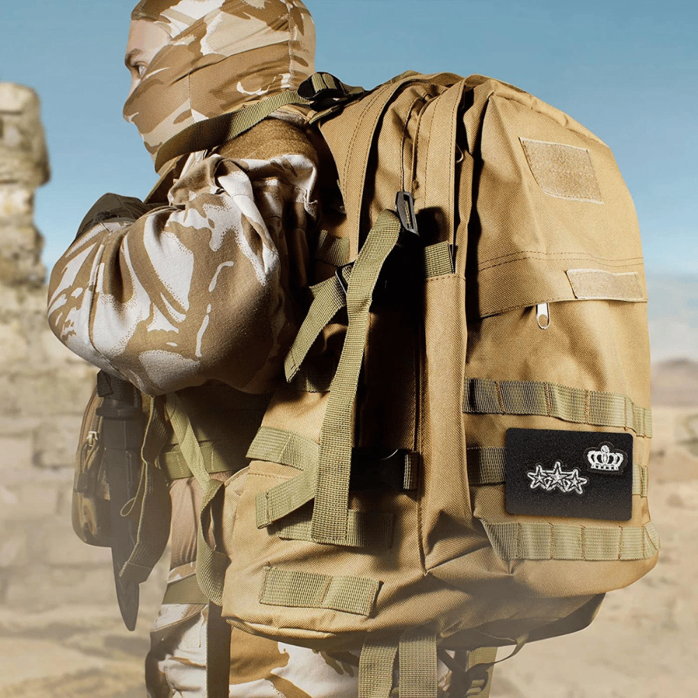 Black MOLLE Panel attached to a tan backpack being carried by a man dressed in tan camo