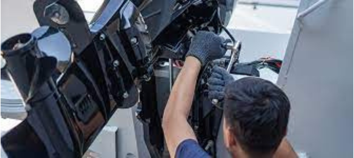 A man using a ratchet and socket to work on his boat motor with it raised up.