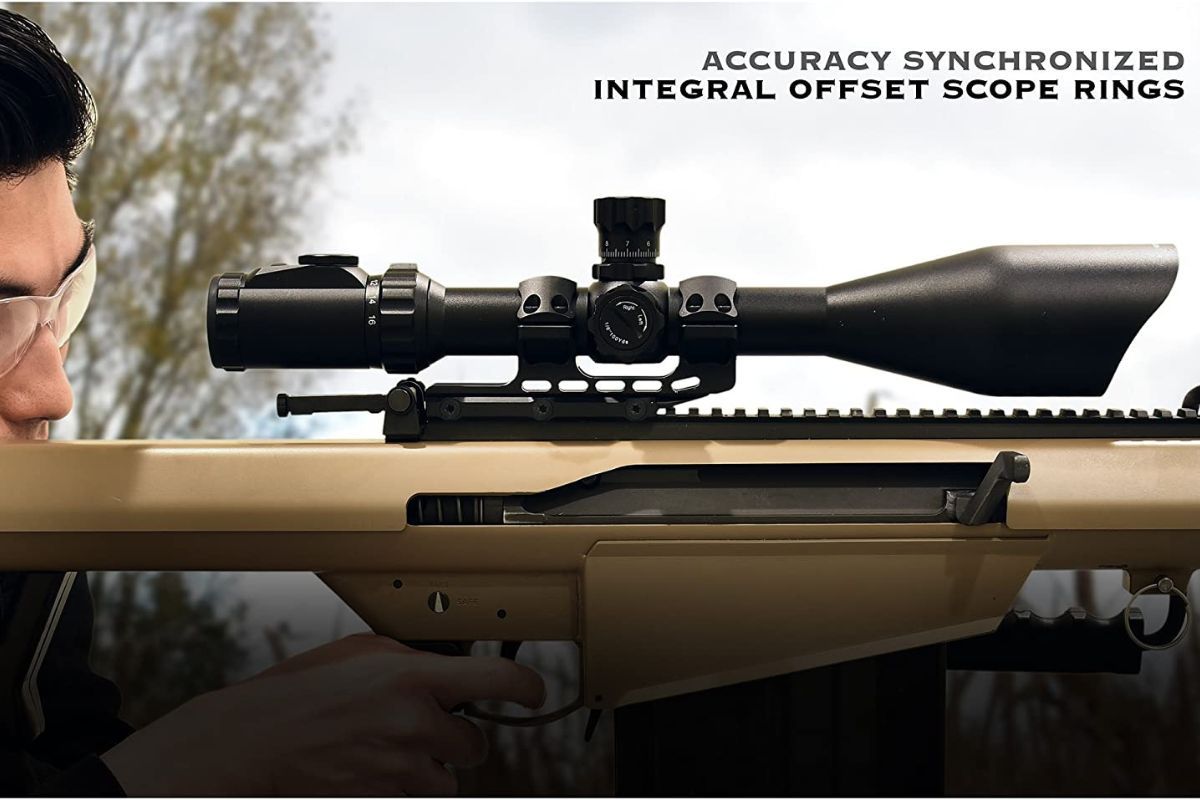 A scope mounted with a one piece mount on a tan Barrett 50 BMG and a man is aiming it to shoot.