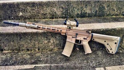 FDE AR15 with tactical optic laying on dirty colored concrete steps