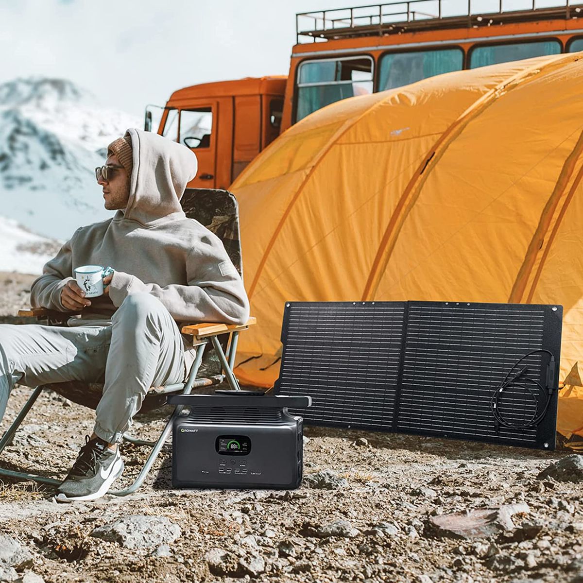 A man in a lawn chair with a Growatt hybrid inverter powering his camp at the base of the mountains.