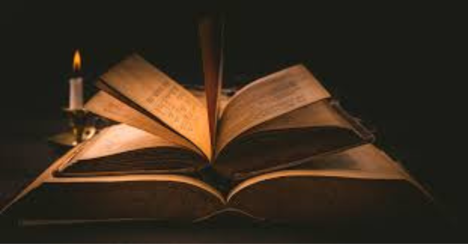 A bible, open, sitting in a desk with a candle burning and another book laying on top of the bible.