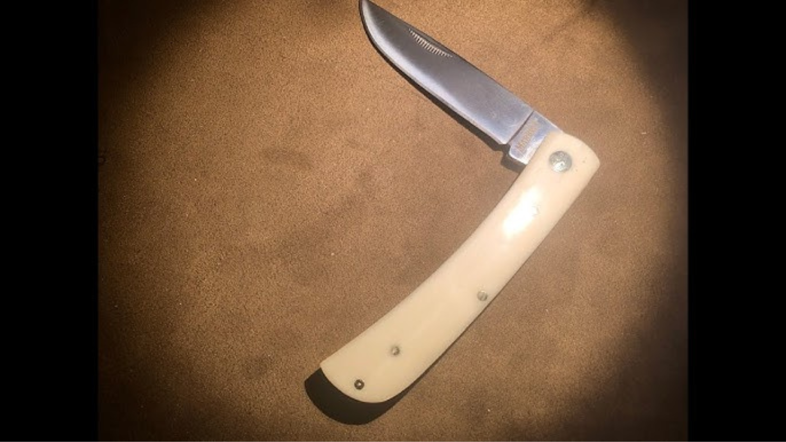 A smooth white bone handle work knife on a table