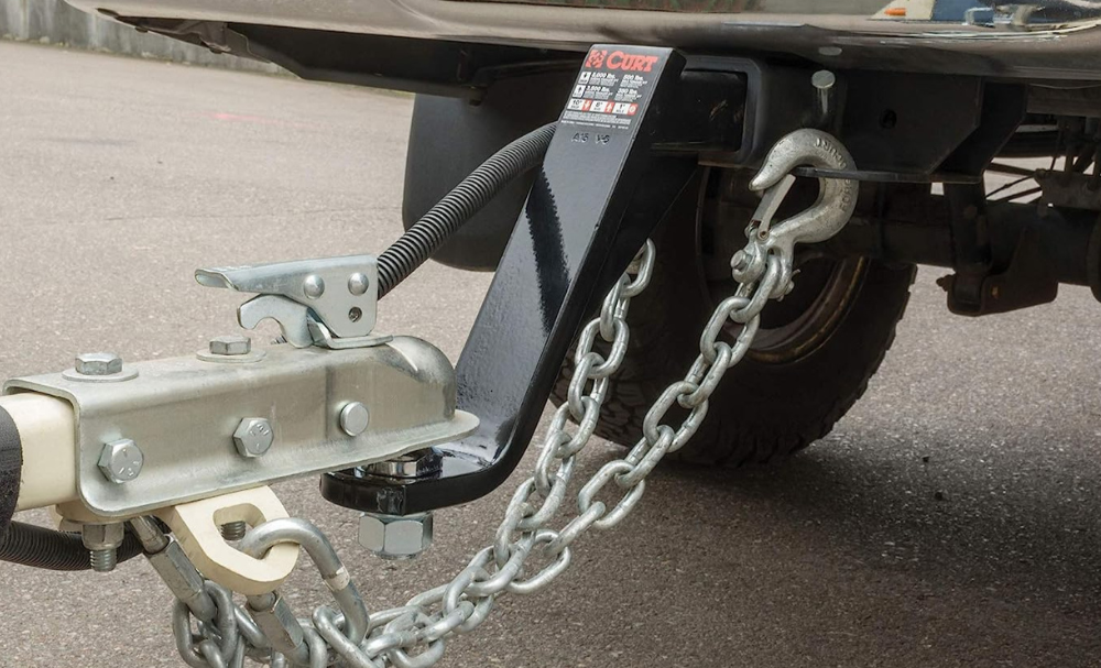 A Curt drop hitch with a trailer on a truck with large tires.