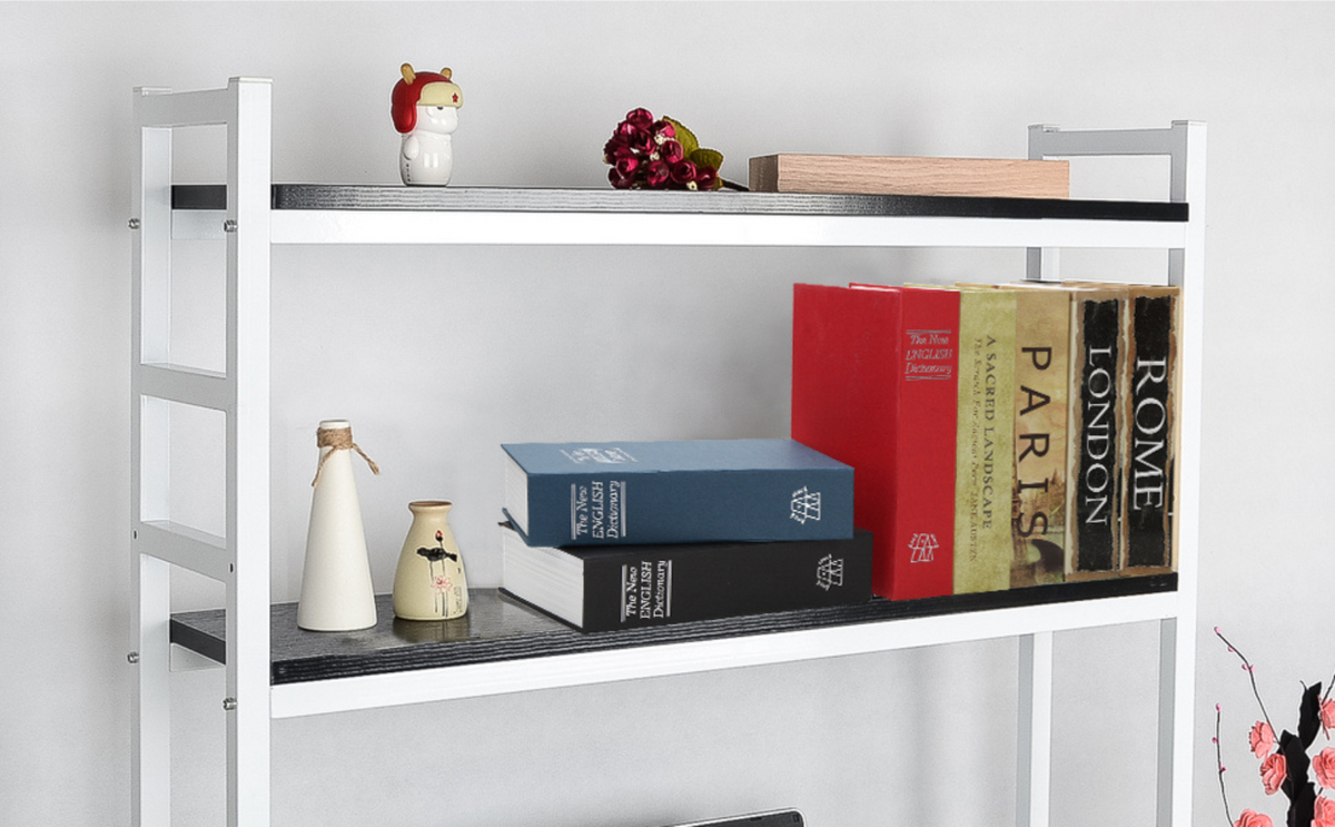 A white bookshelf with books and other knick knacks and a dictionary book gun safe.