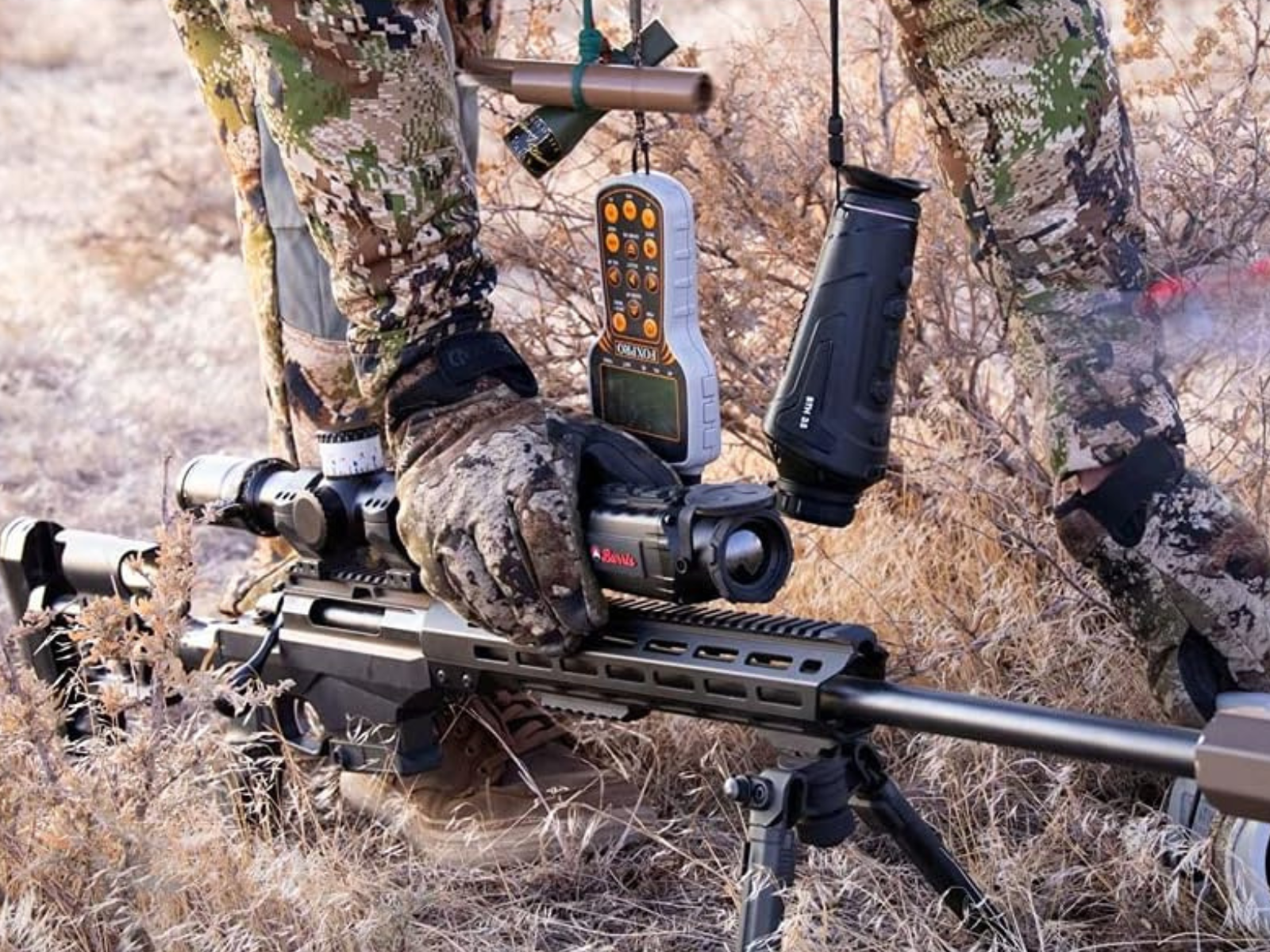 A man in camo with his gloved hand on his Burris Thermal Scope and the rifle on a bipod.