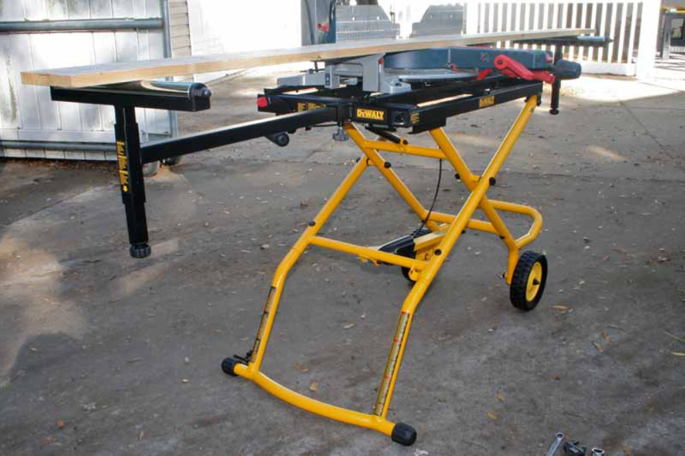 A miter saw stand set up and loaded with a saw and a board on both ends rollers.
