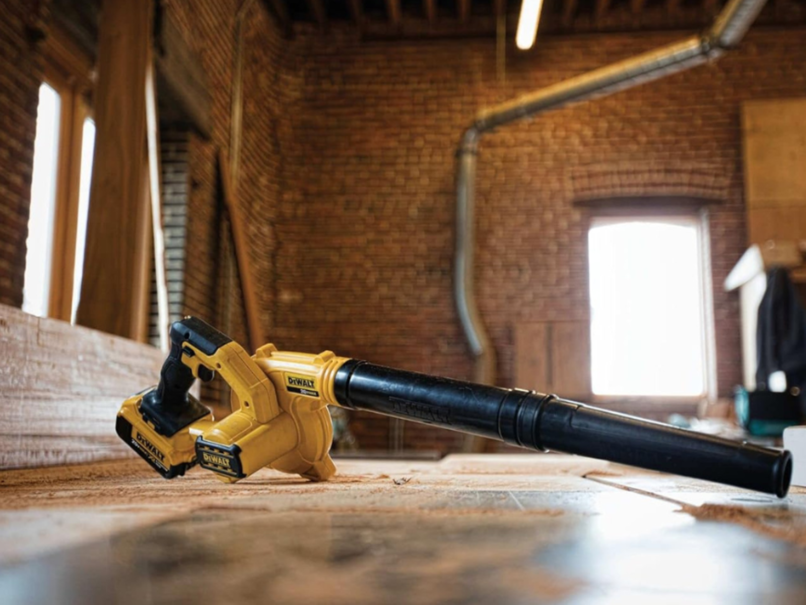 A DeWalt cordless blower sitting on a floor inside a brick building.