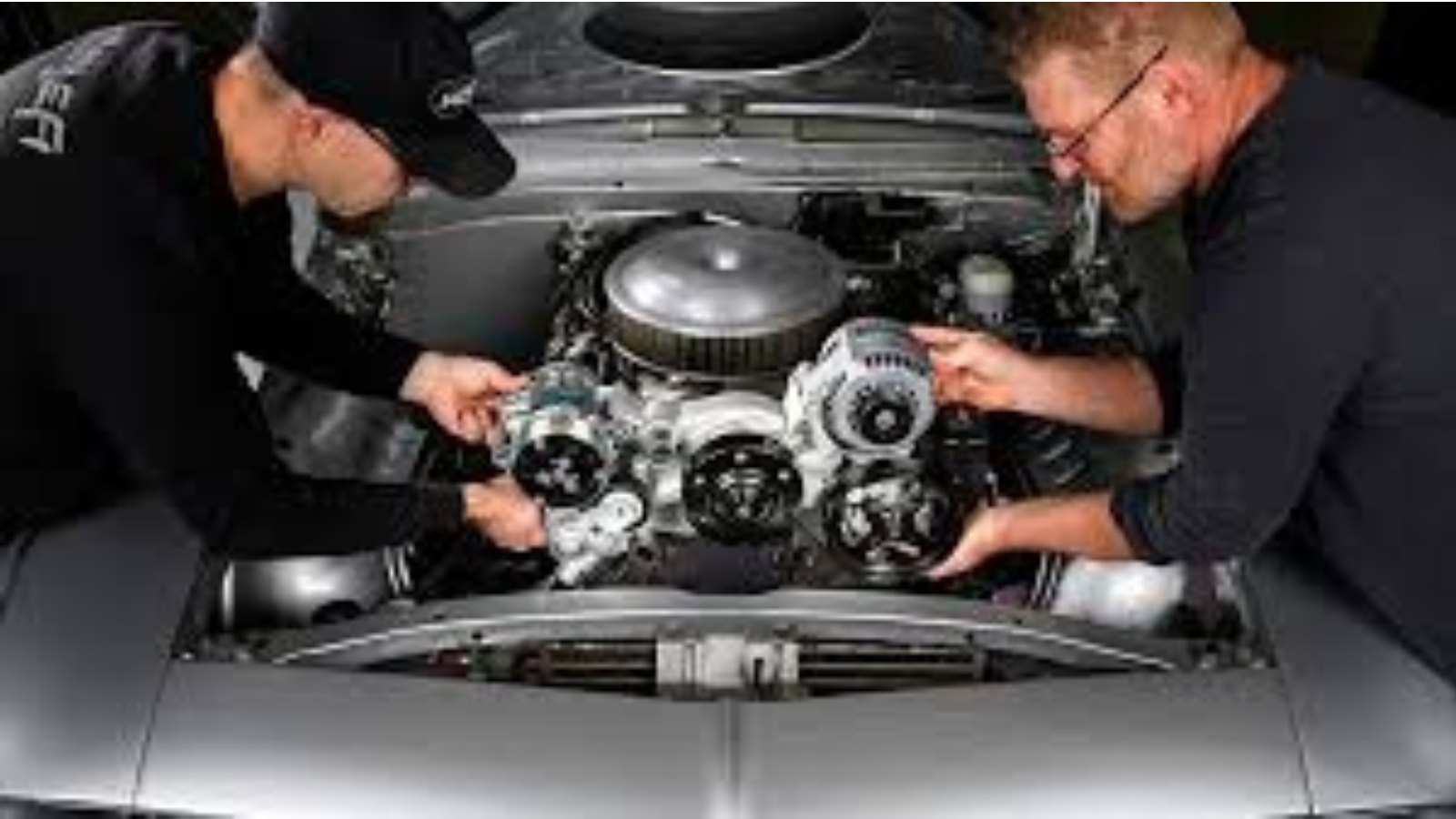 Two men working on an LS engine that has been swapped into a compact car.