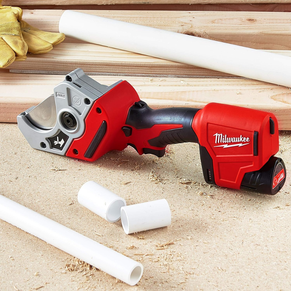 A cordless PVC cutter sitting on wood with saw dust and pieces of PVC pipe.