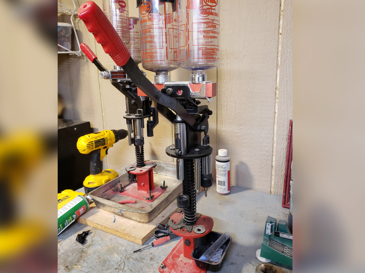 A shotgun reloader mounted on a bench with tools.