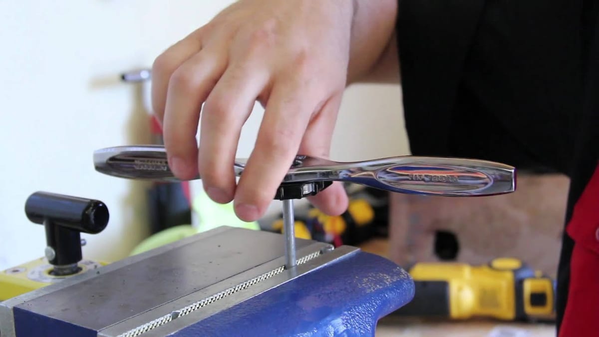 A man using a die on a rod in a vise.