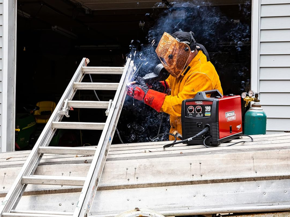 A man using a spoolgun to weld an aluminum ladder.