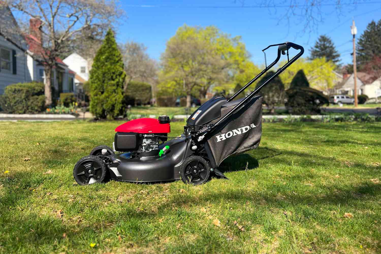 A Honda mower sitting in a yard in a subdivision ready to work!