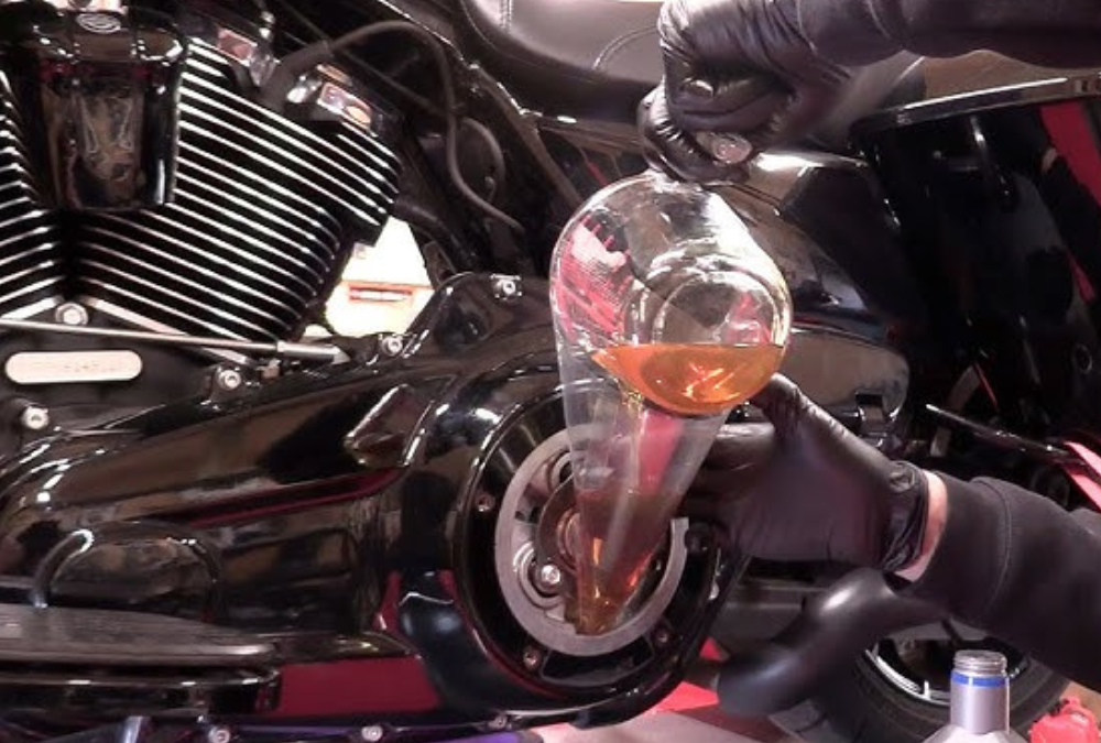 A man pouring primary oil into the primary case on a Harley Davidson