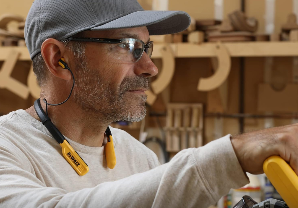 A man wearing earbuds by DeWalt while working.