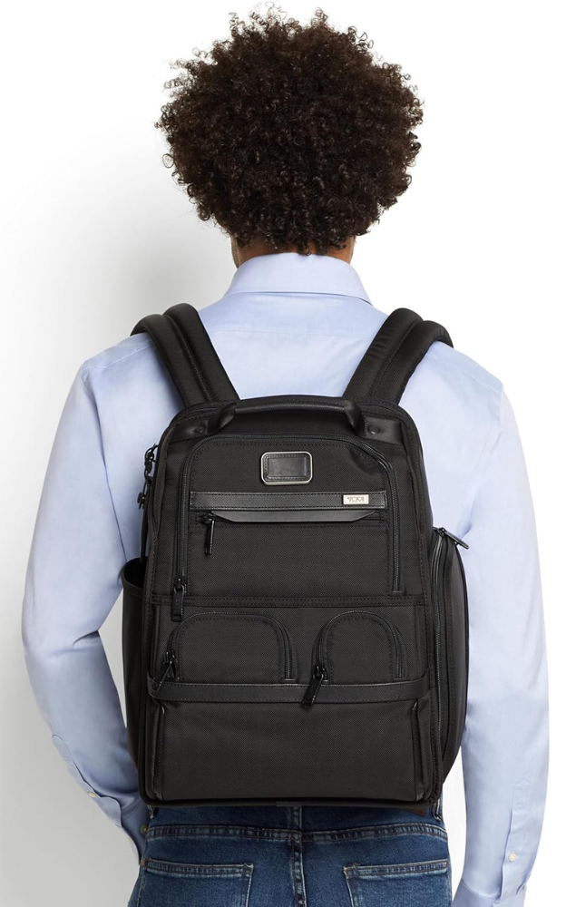 A man facing away while wearing a travel backpack by Tumi