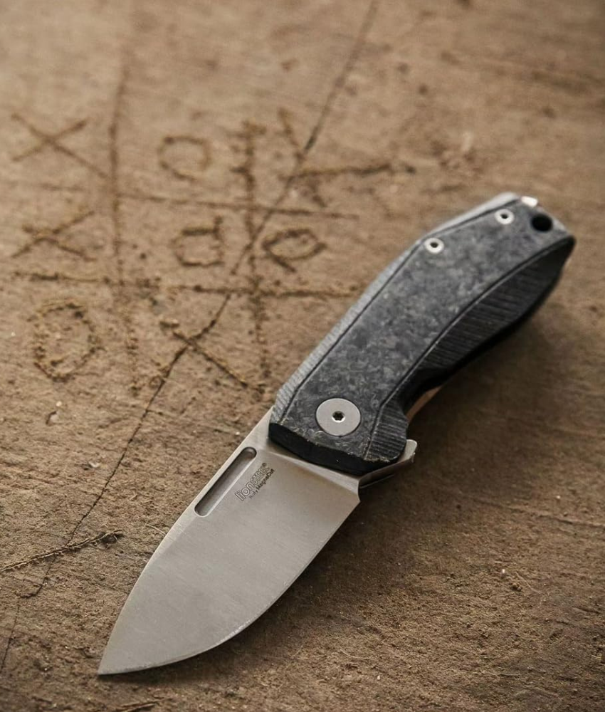 A knife opened on wood showing the Magnacut steel finish