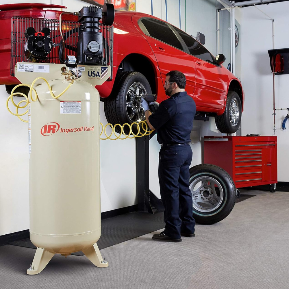 A man removing a car tire with an air tool fed by an Ingersoll Rand air compressor